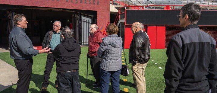 a group of era members stand on memorial field and listen to a tour leader